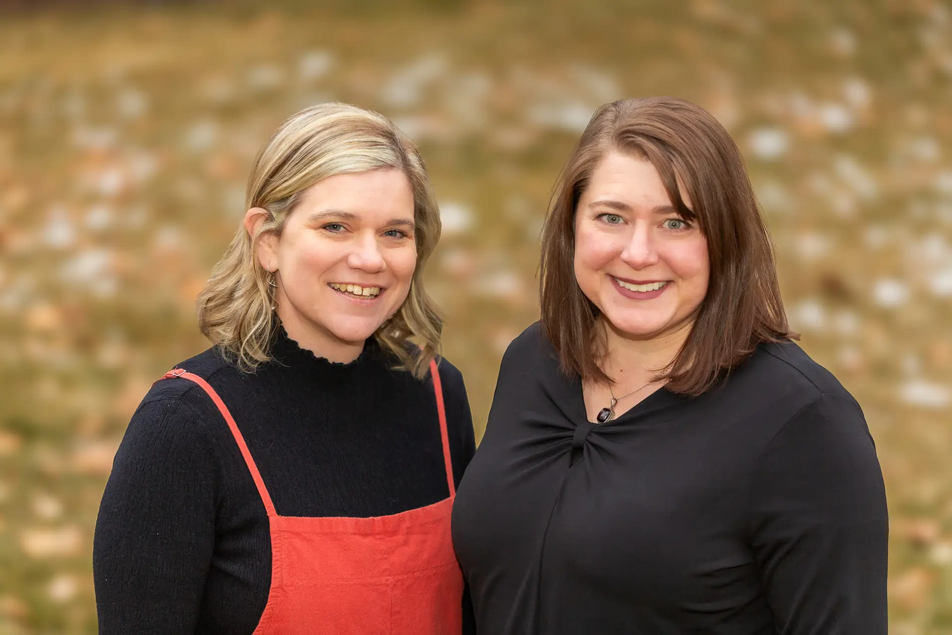 Two women standing side by side smiling at camera